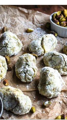 several cookies are sitting on a piece of wax paper next to a bowl of pistachios