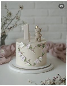 a white cake decorated with flowers and a teddy bear