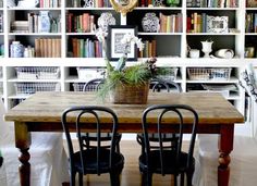 a dining room table and chairs with bookshelves in the backgroung