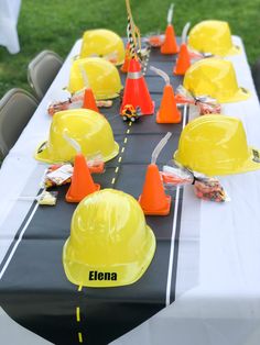 construction themed table setting with yellow hard hats and orange cones on the long black table