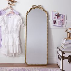 a large mirror sitting on top of a wooden floor next to a white chest of drawers