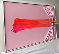 a pink painting hanging on the wall next to a bed