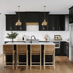 a kitchen with black cabinets and white counter tops, wooden flooring and pendant lights over the island