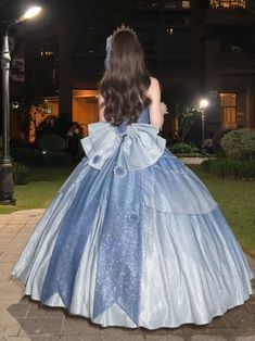 a woman in a blue dress is walking down the street at night with her back to the camera