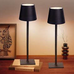 two black lamps sitting on top of a wooden table