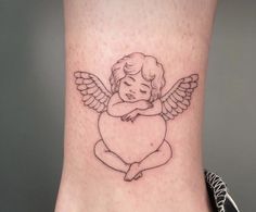 a small angel tattoo on the back of a woman's leg, with wings