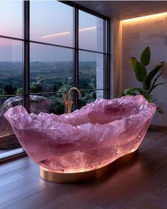 a large pink rock sitting on top of a wooden floor in front of a window