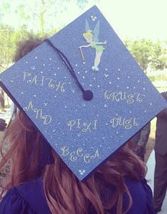 a woman wearing a blue graduation cap with the words faith, trust, and pixies on it