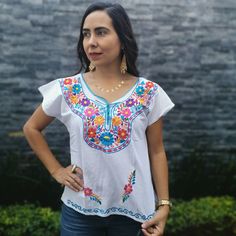 This handmade Mexican shirt has been embroidered with beautiful colorful flowers. It will look great with any color skirt or pants. It has short sleeves and a scoop neckline. This is a nice comfortable casual cotton shirt. It is perfect as a gift for a friend or someone special. About Our Items: Each one of our items is handmade/hand woven by Indigenous communities of Chiapas and Oaxaca in Mexico. Great care has been taken to ensure the quality and uniqueness of each item we sell. Our items are White Embroidered Beach Shirt, Bohemian Shirt With Multicolor Embroidery, White Floral Embroidered Beach Shirt, Casual Multicolor Top With Intricate Embroidery, White Floral Embroidered Top For Festivals, White Floral Embroidered Shirt For Beach, Casual Tops With Intricate Embroidery For Festivals, White Floral Embroidered Shirt For The Beach, White Embroidered Top With Floral Print Short Sleeve