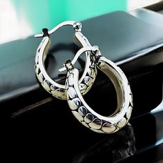 Elevate your jewelry collection with our exquisite Lightweight Oval Cobblestone Design Hoop Earrings, meticulously crafted from premium 925 Sterling Silver. Each earring boasts a delicate hollow construction, ensuring both comfort and elegance. The dimensions of these sophisticated hoops are approximately 18.5 mm in width and 21.4 mm in length, offering a striking presence without overwhelming. They are subtly stamped with '925' to certify their sterling silver composition. Experience the perfec Luxury Silver Tarnish-resistant Huggie Earrings, Luxury Silver Huggie Earrings With Polished Finish, Luxury Round Sterling Silver Huggie Earrings, Luxury Silver Round Huggie Earrings, Tarnish Resistant Sterling Silver Oval Earrings, Silver Oval Huggie Earrings For Gift, Silver Oval Huggie Earrings As A Gift, Oval Sterling Silver Huggie Earrings For Gift, Silver Huggie Fine Jewelry