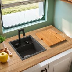 a kitchen sink and cutting board on a counter top next to a window with an outside view