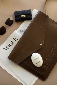 a brown purse sitting on top of a table next to sunglasses