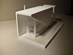 a white model house with a pen on the floor next to it's door