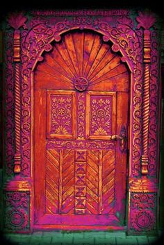 an ornate wooden door with pink paint on it