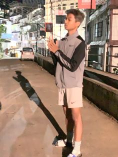 a young man standing on the side of a road