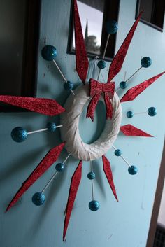 a blue door with a red and white wreath hanging from it's side, surrounded by pins