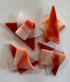 four pieces of red and white glass sitting on top of a table next to each other