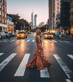 a woman standing in the middle of an empty city street at night with traffic and buildings