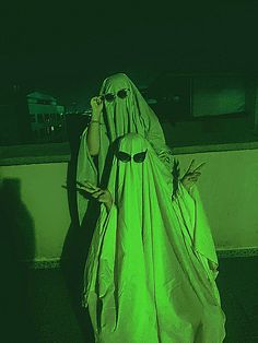 a woman dressed as a ghost holding a cell phone to her ear while standing in the dark