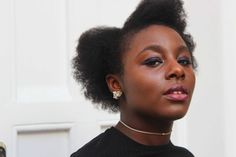 a close up of a person with an afro haircut and wearing a black shirt