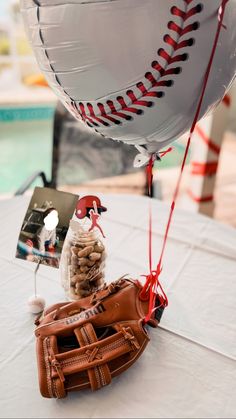 a baseball and glove on a table with balloons in the shape of a ballon