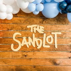 balloons and the word the sandlot on a wooden background with white and blue balloons