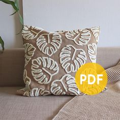 a brown and white pillow sitting on top of a couch next to a potted plant