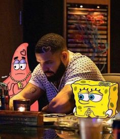 a man sitting at a table with a spongebob paper cut out in front of him