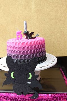 a black and white photo of a birthday cake with a bat decoration on the top