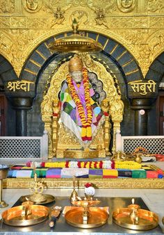 there is a golden statue in the middle of some gold plates and bowls on the floor