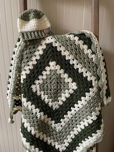 a green and white crocheted blanket sitting on top of a wooden chair next to a wall