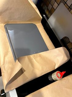 an open laptop computer sitting on top of a piece of brown paper next to a pair of scissors