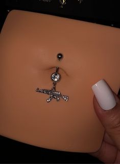 a person holding onto a fake belly ring with a cross on it