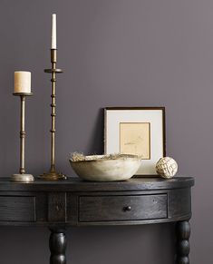 a wooden table with a bowl and two candles on it next to a framed photograph