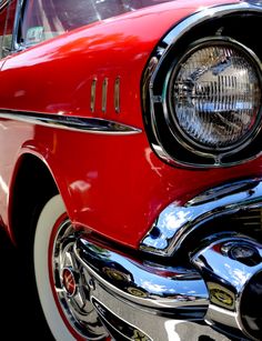 the front end of an old red car with chrome rims and headlamps