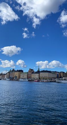 a large body of water with buildings on the shore and clouds in the sky above