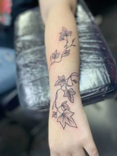 a woman's hand with a tattoo on it that has flowers growing out of it