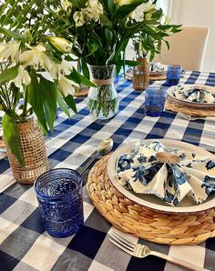 a blue and white table setting with flowers in vases