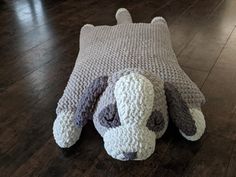 a crocheted dog laying on top of a wooden floor