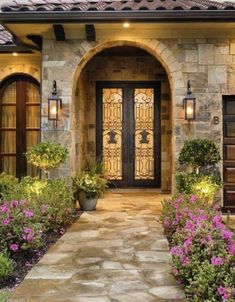 the front entrance to a house with flowers and plants in blooming pots on either side