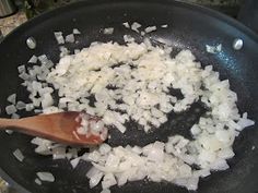 onions are being cooked in a pan with a wooden spoon on the side and other ingredients