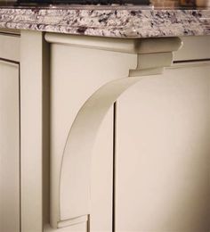 the corner of a kitchen cabinet with marble counter tops and white cabinets in front of a stove