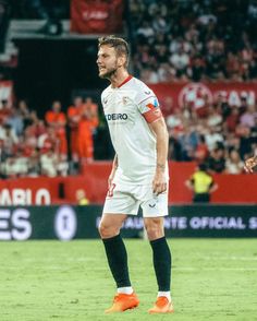 a man standing on top of a field next to a soccer ball in front of a crowd