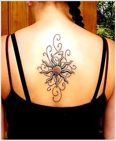 the back of a woman's neck with an intricate sun tattoo on her left shoulder