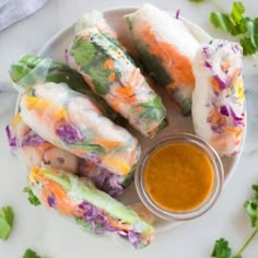 several vegetable spring rolls on a plate with dipping sauce