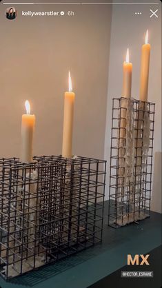 four lit candles sitting in front of a metal container on top of a countertop