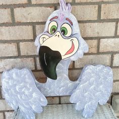 a white bird statue sitting on top of a wicker chair next to a brick wall