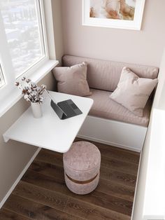 a small white table sitting next to a couch in a living room under a window