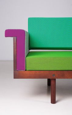 a green and pink couch sitting on top of a wooden frame