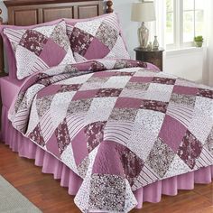 a bed with a purple and white quilt on it